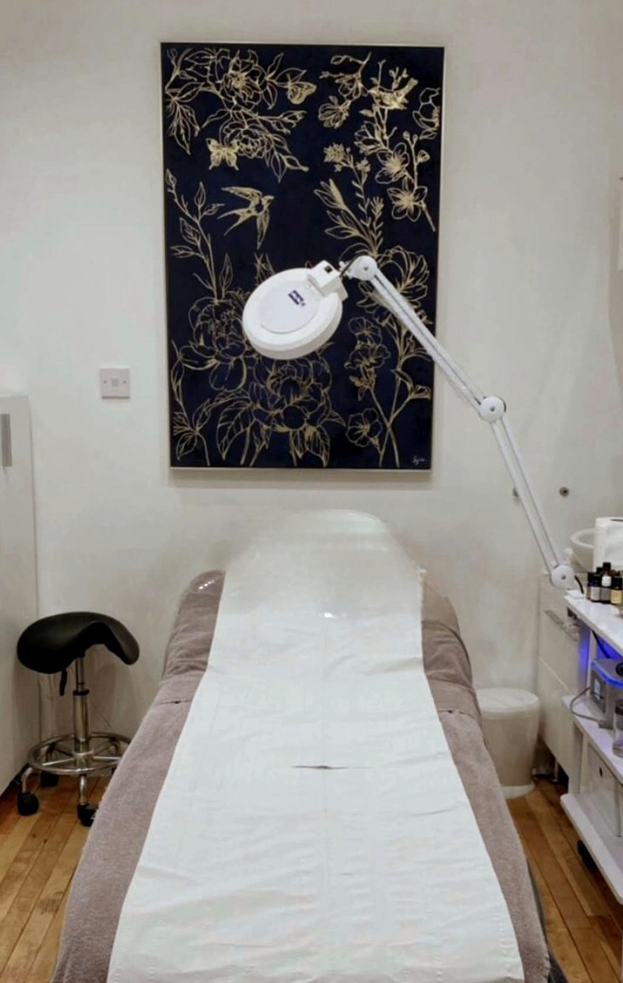 The treatment room, with a couch, treatment lamp and a navy and gold botanical print
